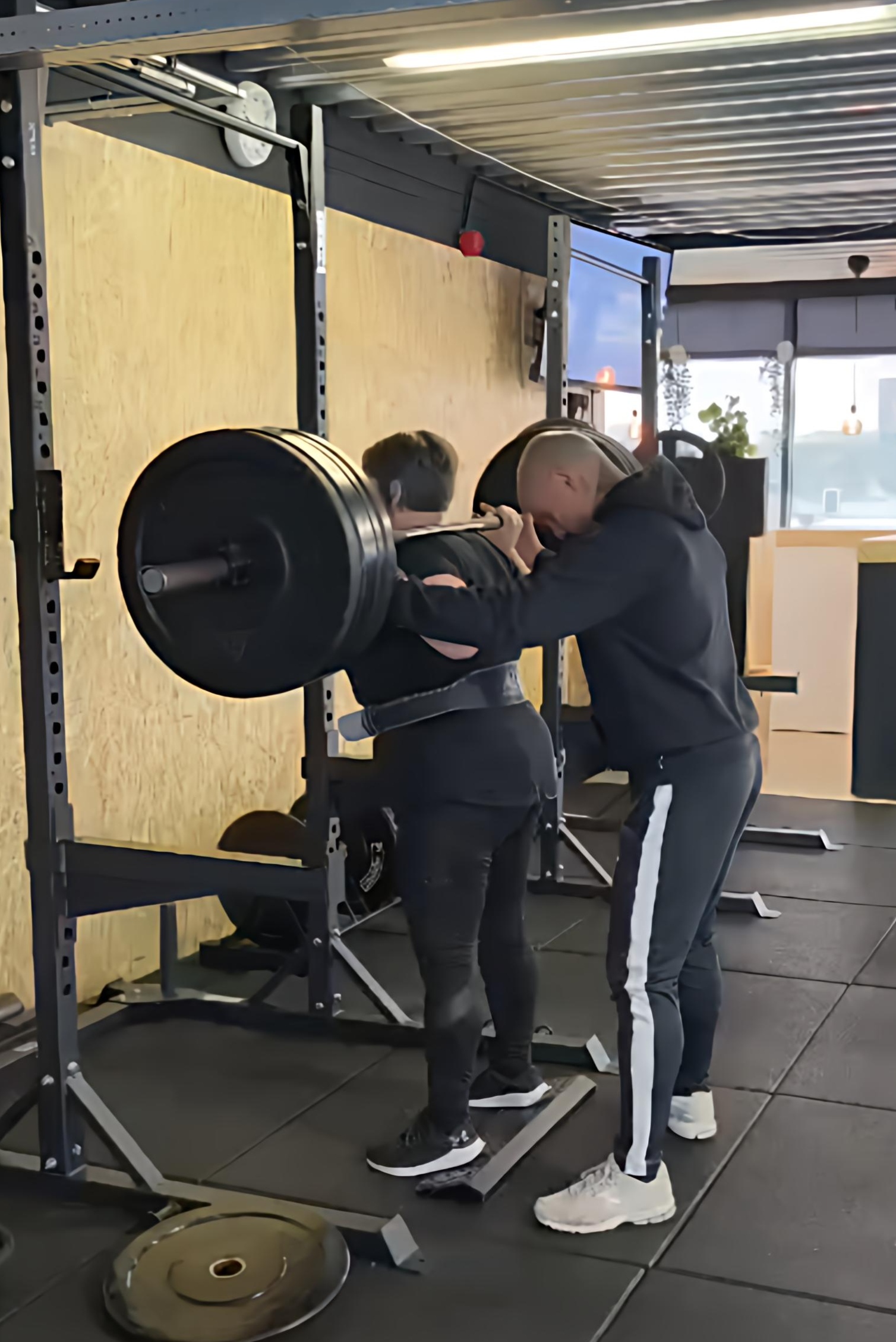 Coach begeleidt een klant bij een squat met bar