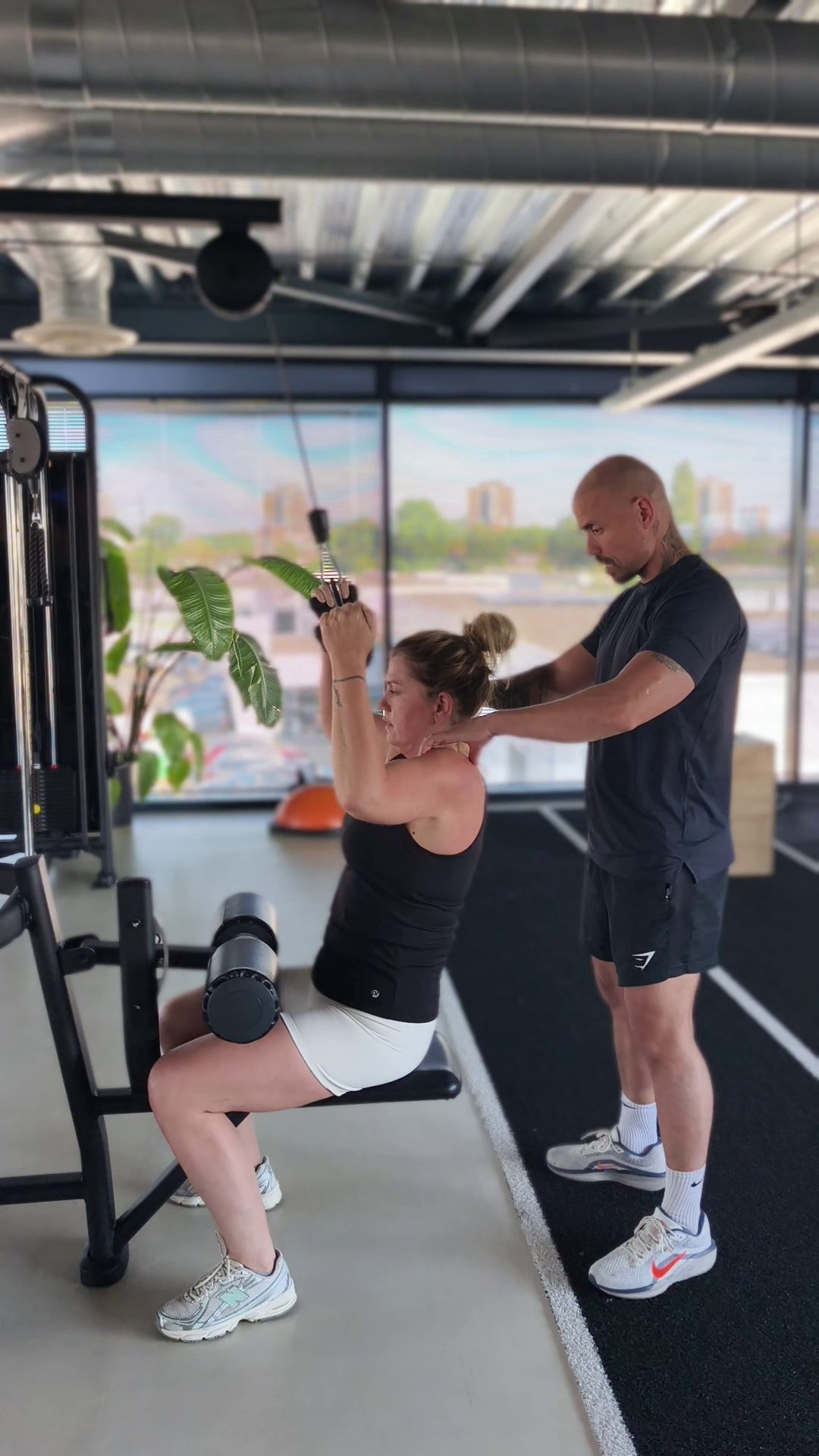 Personal trainer coacht een sporter tijdens een kabeltrainingsoefening bij Fit Up Leiderdorp