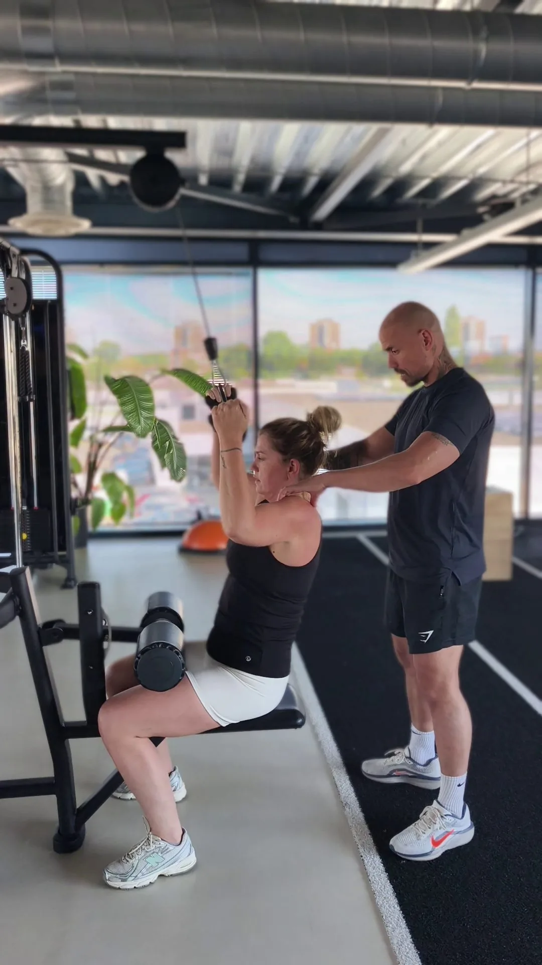 Personal trainer coacht een sporter tijdens een kabeltrainingsoefening bij Fit Up Leiderdorp