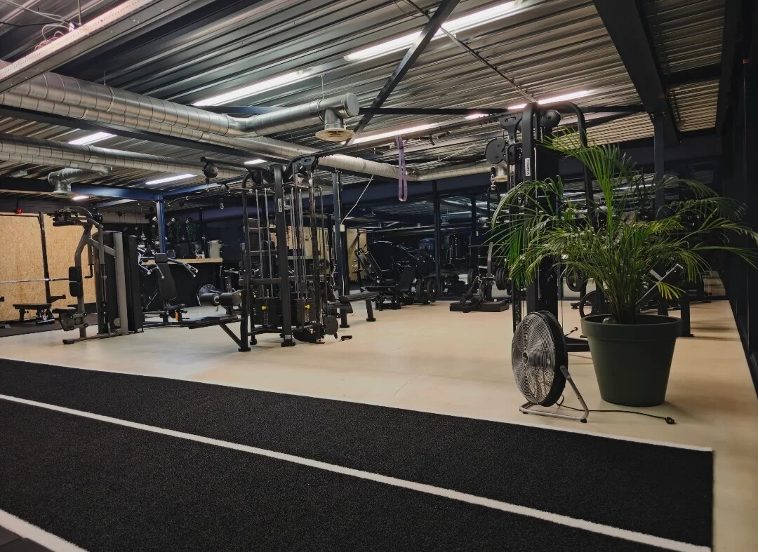Interieur van Fit Up Leiderdorp — ruime gym met kabeltoren, racks en sprintbaan