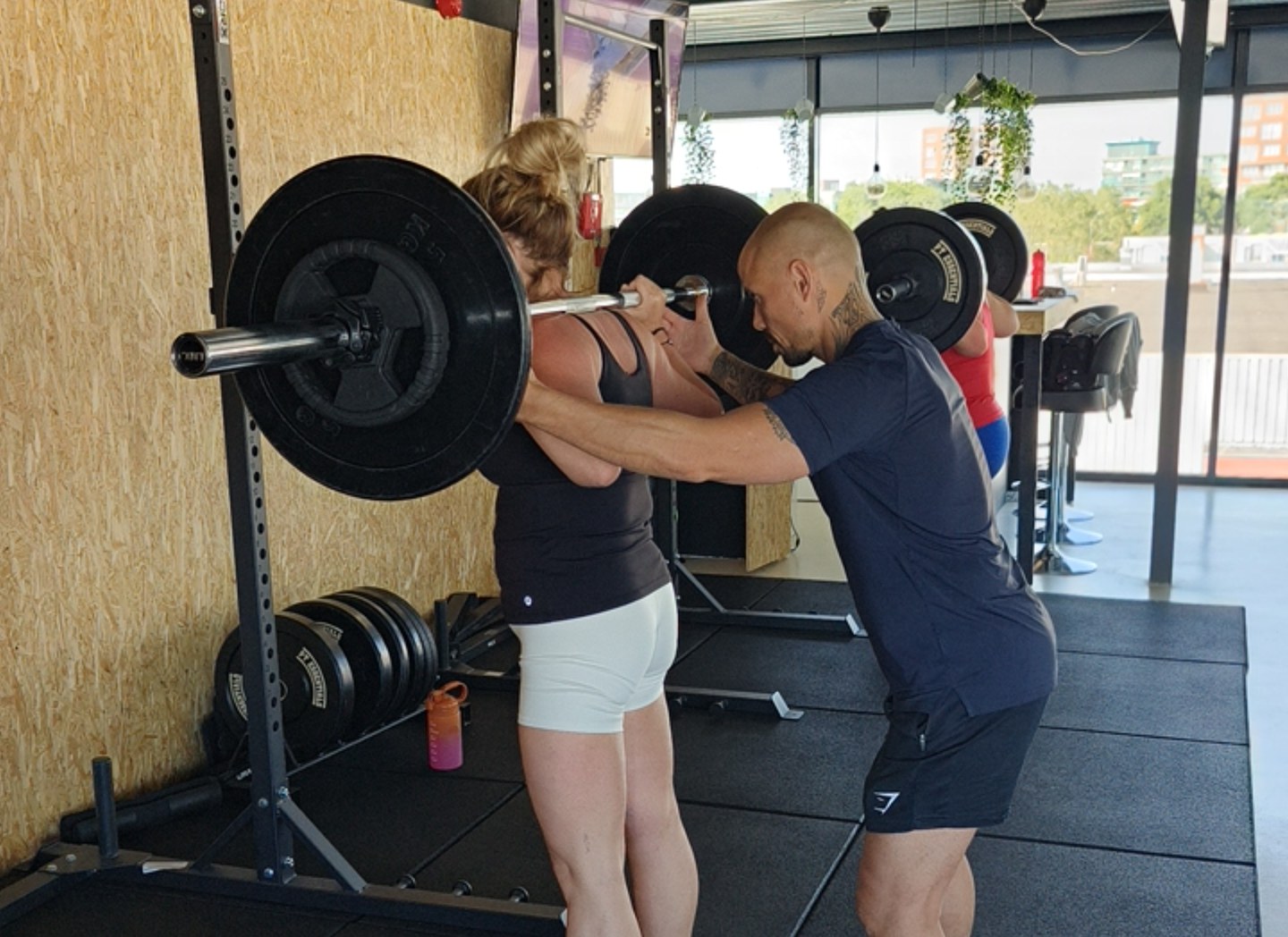 Personal trainer spot een klant tijdens een squat bij Fit Up Leiderdorp
