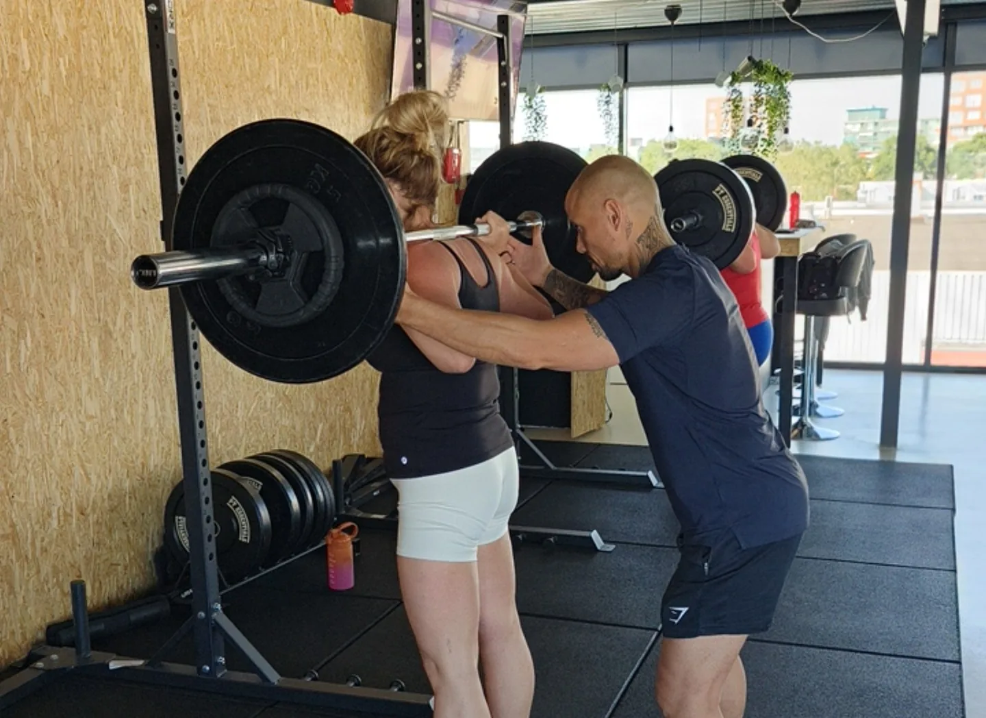 Personal trainer spot een klant tijdens een squat bij Fit Up Leiderdorp